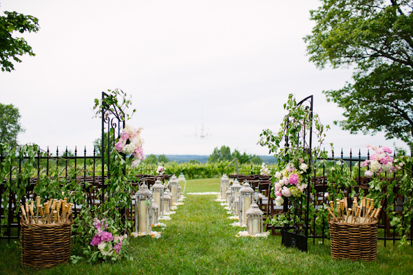 Garden wedding ceremony with lush pink flowers and umbrellas for guests - photo by Dan Stewart Photography